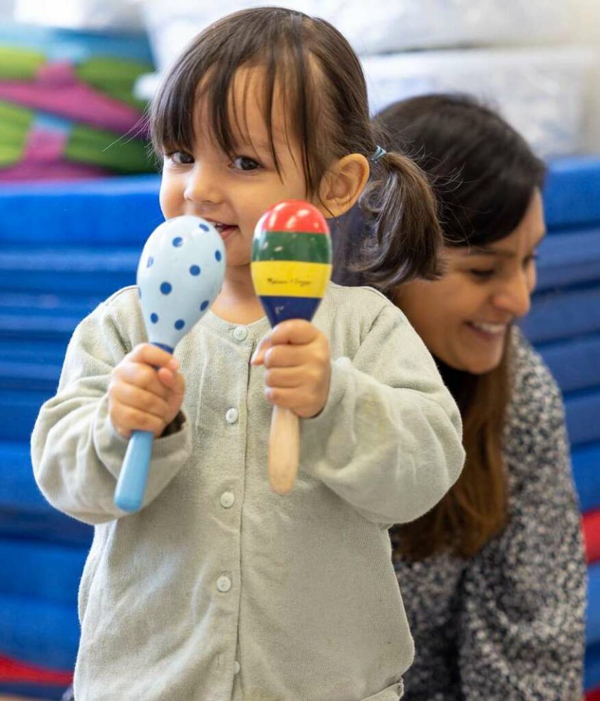 Barn spelar maracas tillsammans med pedagog på förskolan